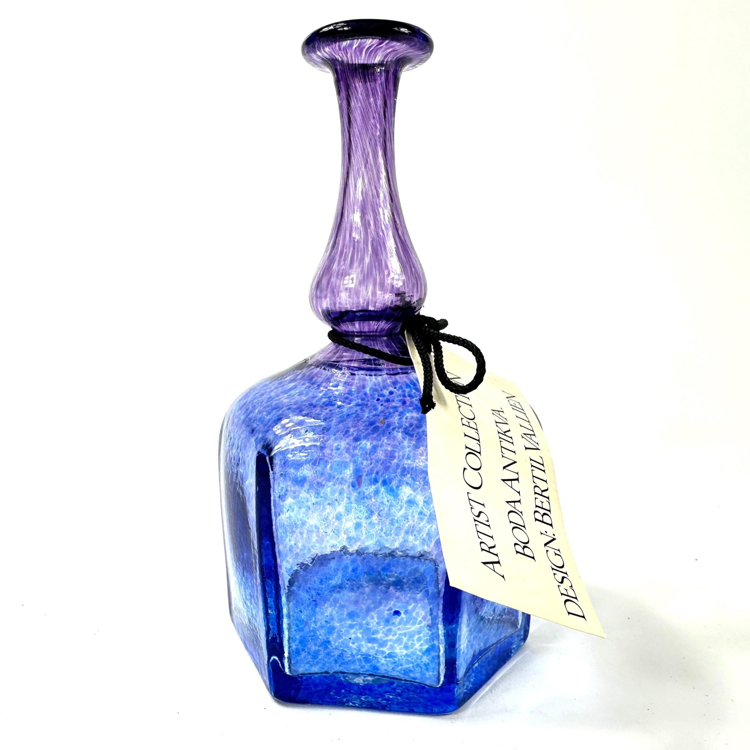 Kosta Boda Antika art glass bottle by Bertil Vallien, deep blue faceted body with purple pulled neck, full front view