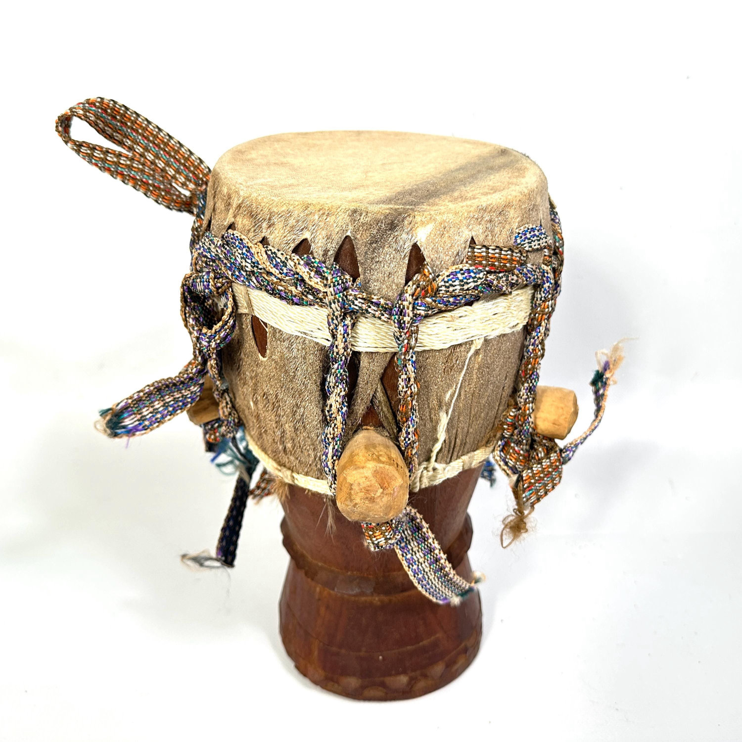 Medium African hand drum photographed from above showing woven rope handles, natural hide drumhead texture, and wooden bindin