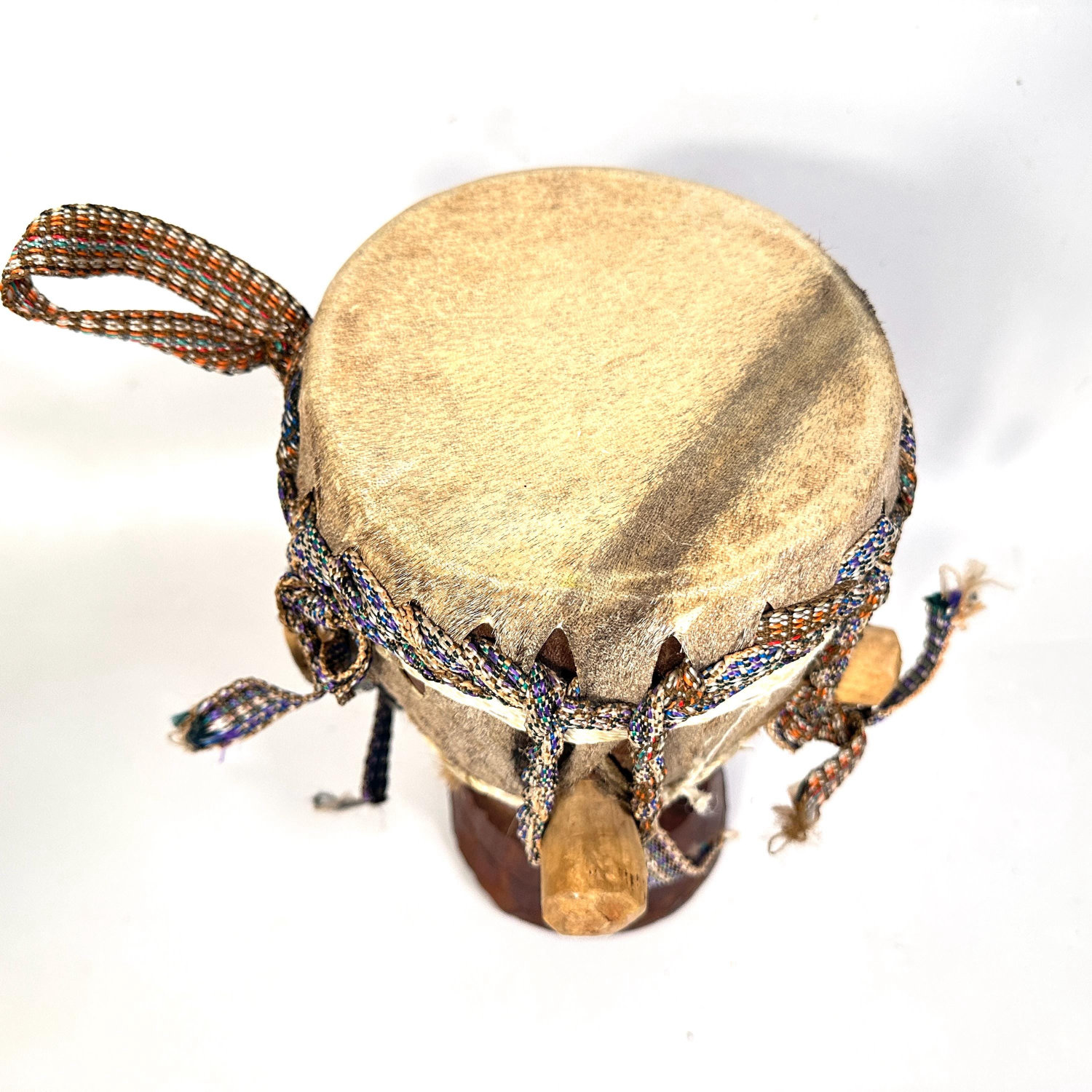 Medium African hand drum with woven rope handles displayed from above, showing aged natural hide and wooden tuning peg arrang