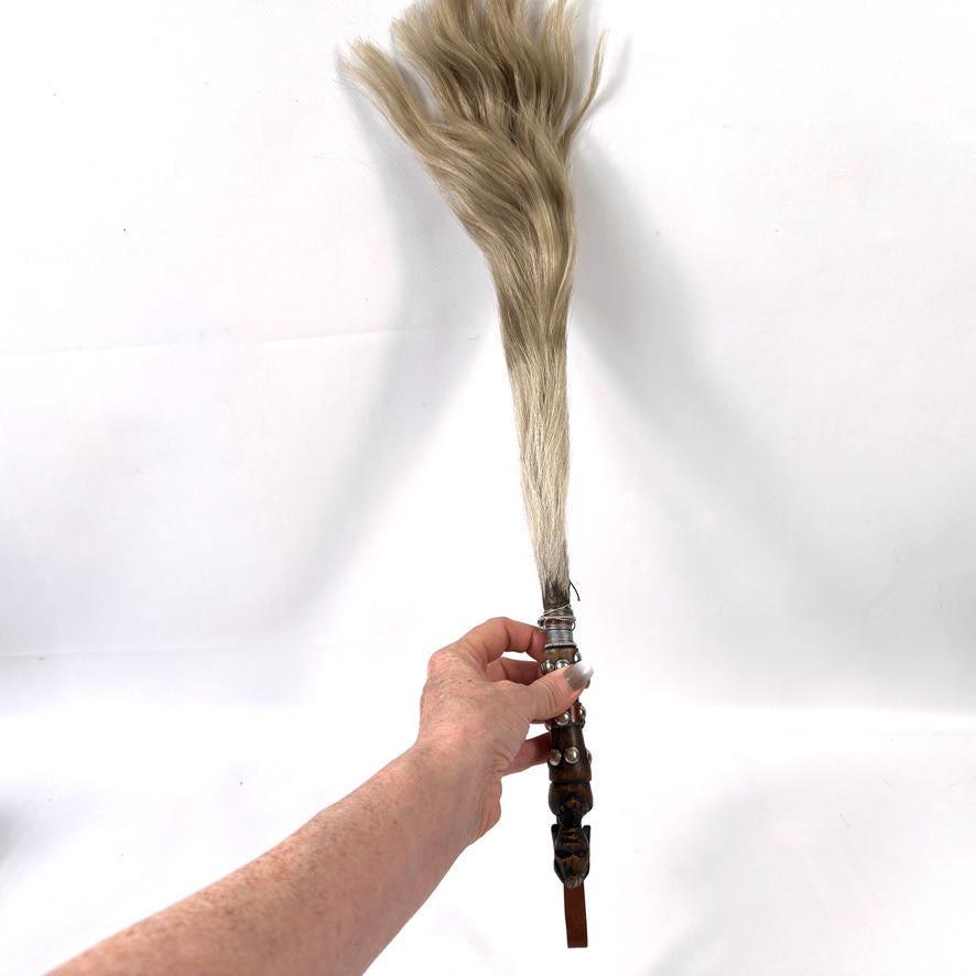 Overhead hand-held view showing horsehair bristle volume and natural texture, with carved wooden handle held upright