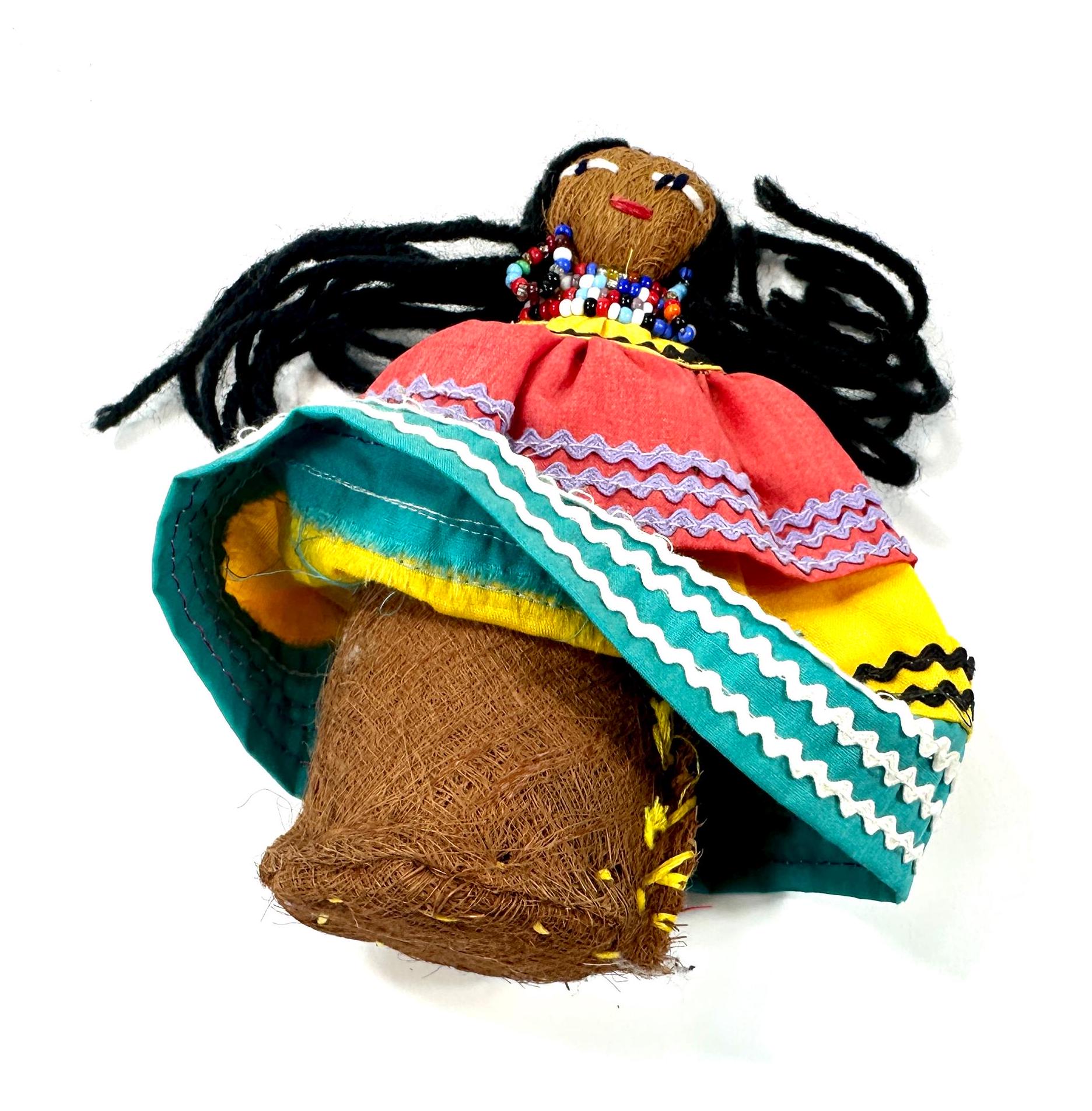 Overhead view of doll lying on patterned textile surface, revealing skirt layers, hair arrangement, and dimensional clothing
