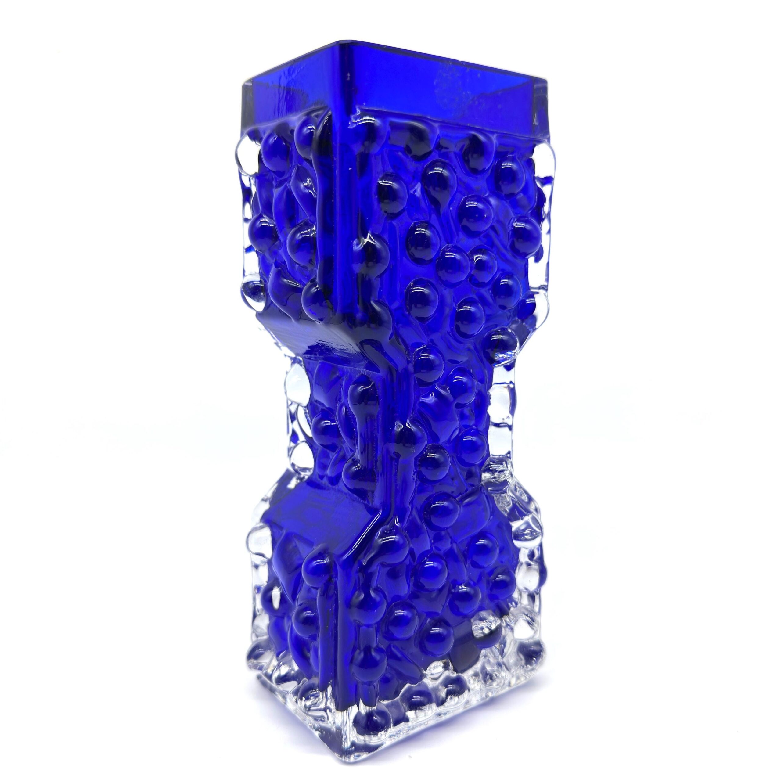 Pressed glass vase angled view showing textured panels, geometric upper form, transparent base structure, three-dimensional d