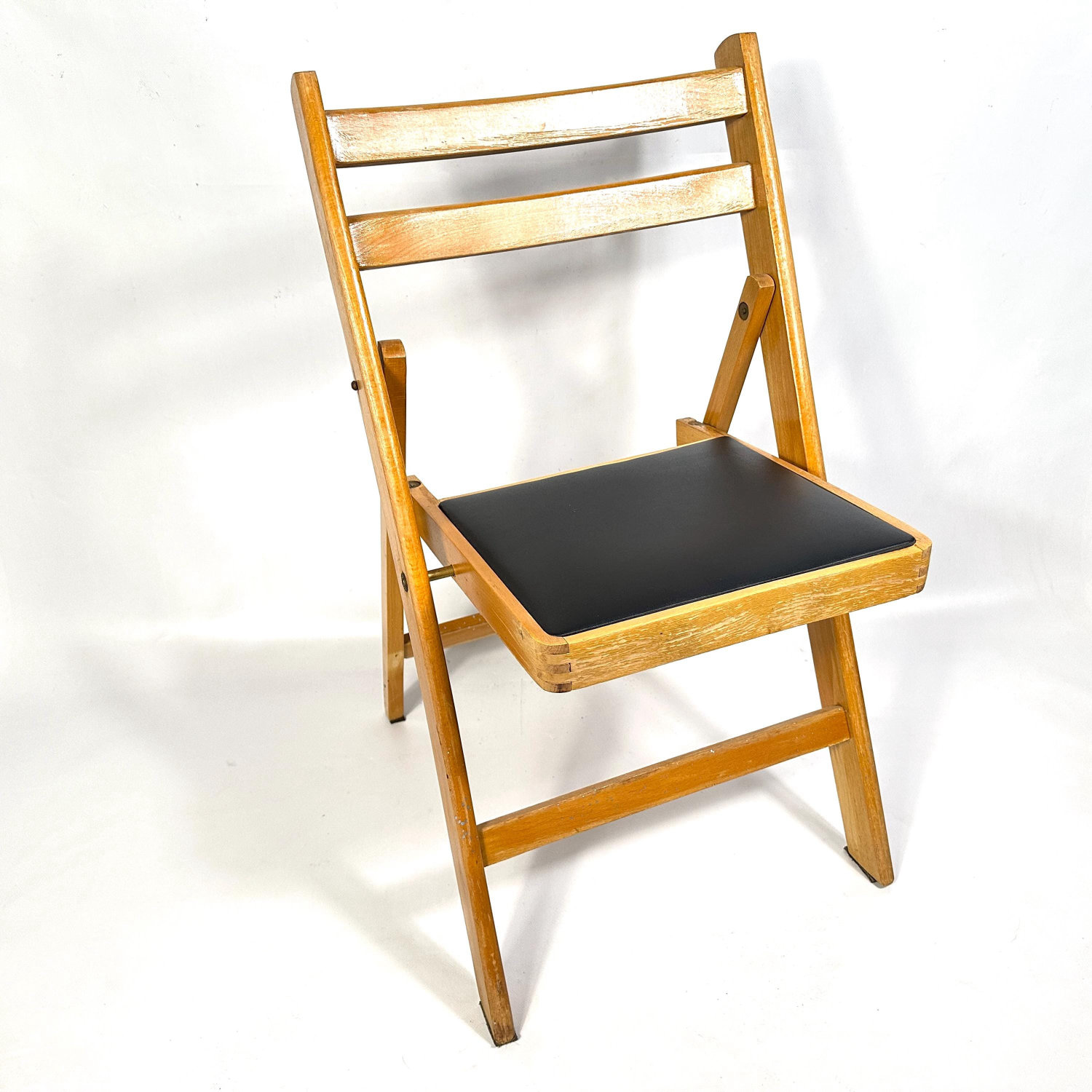 Set of two mid-century folding wooden chairs with light oak frames, curved backrests, and black upholstered seat pads, front 