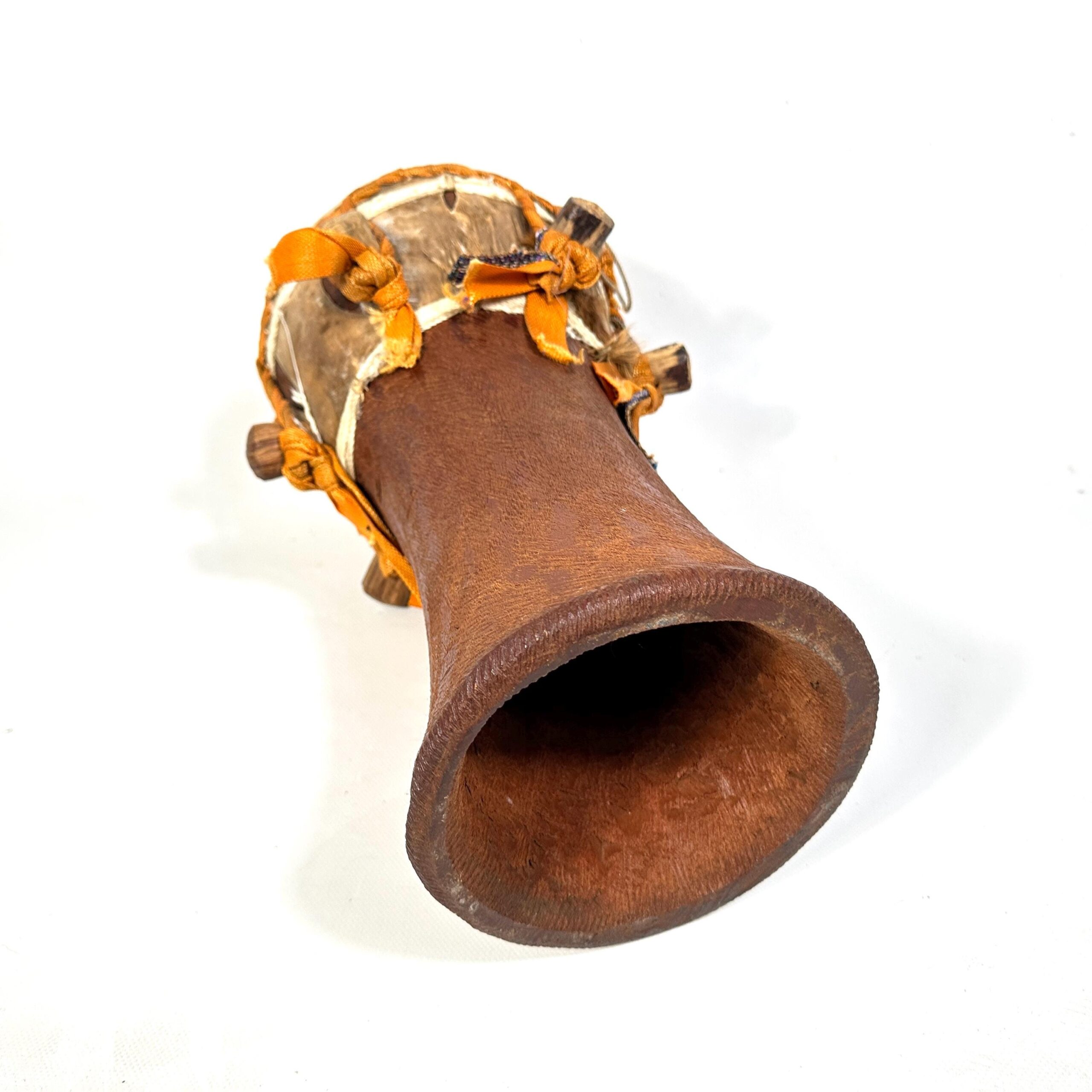 Single African hand drum wooden body photographed at angle showing carved form, rope tensioning system, and natural wood grai