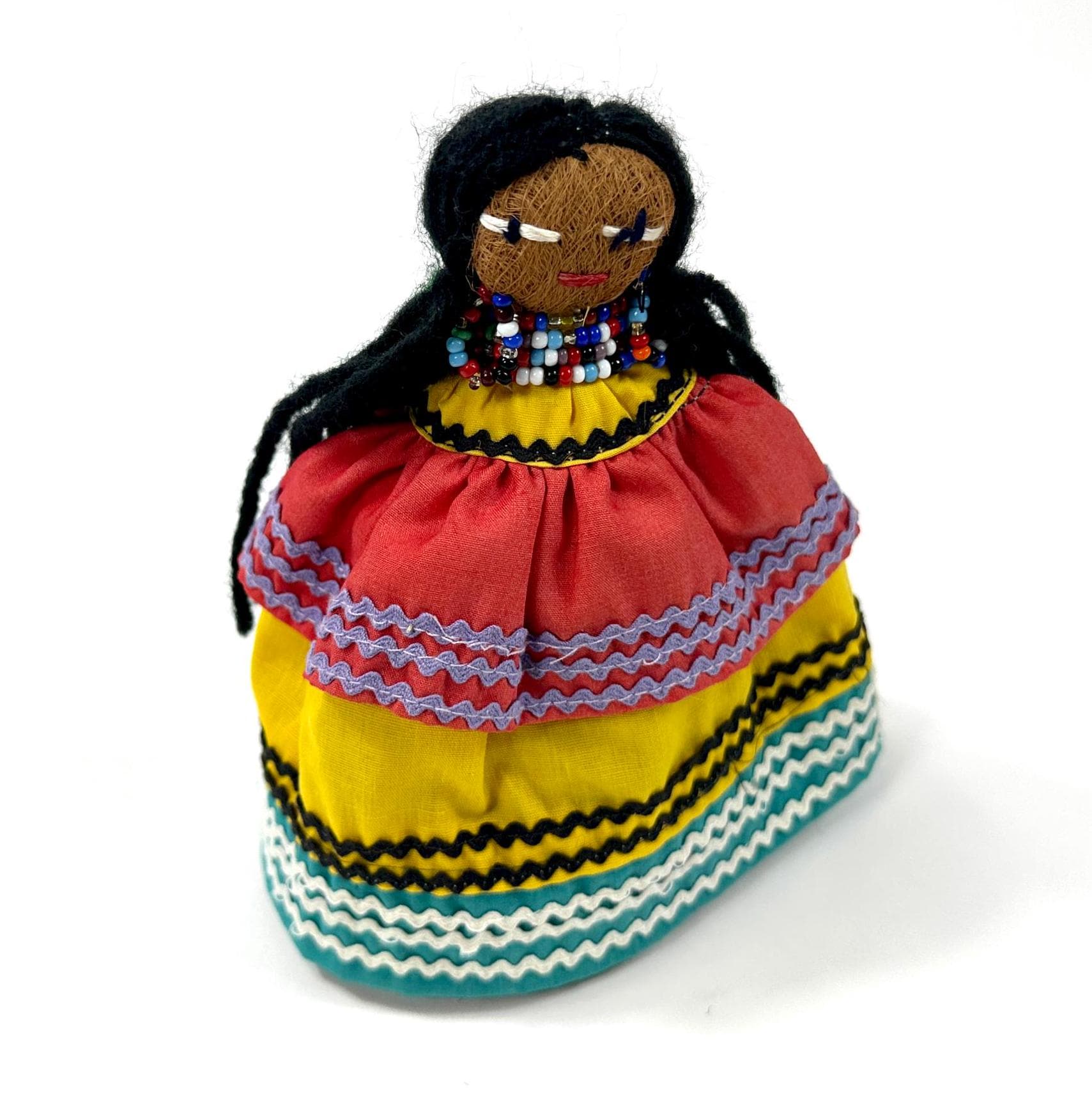 Three-quarter frontal angle showing doll with braided black hair, detailed beaded yoke, and segmented tiered skirt constructi