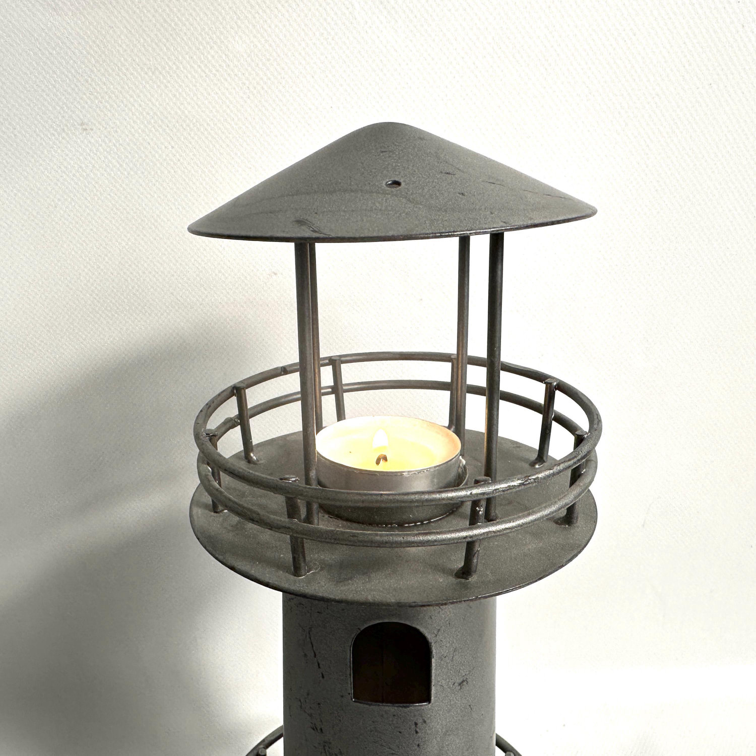 Top-down view of lighthouse candleholder displaying conical roof and upper canopy with metal railing detail