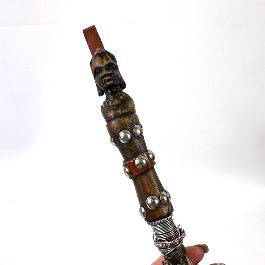 Vertical full-length shot of whisk emphasizing carved wooden head sculpture, metal decoration, and natural horsehair texture