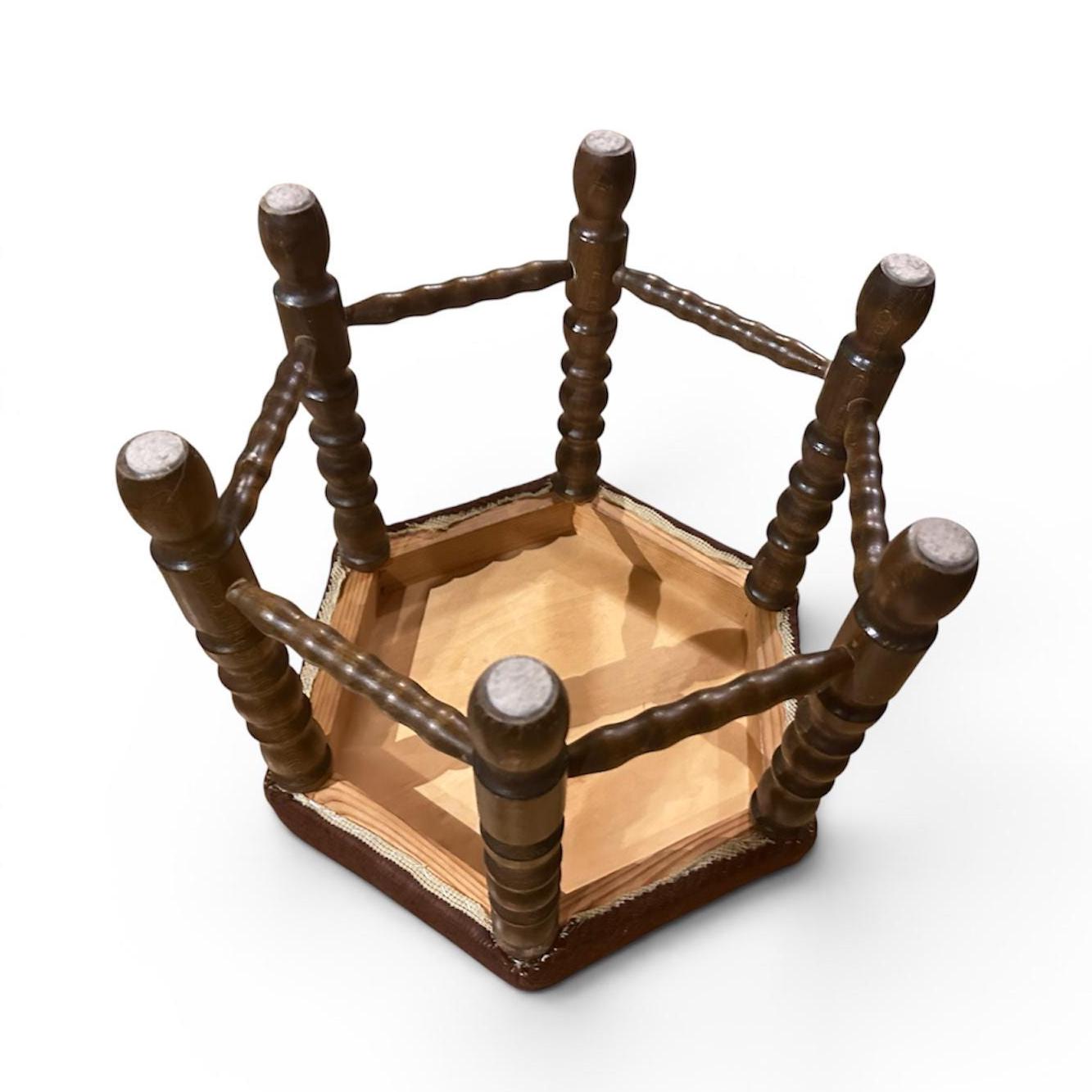 Vintage footstool viewed from above, revealing turned wooden frame construction with cross stretchers, bare wooden base inter