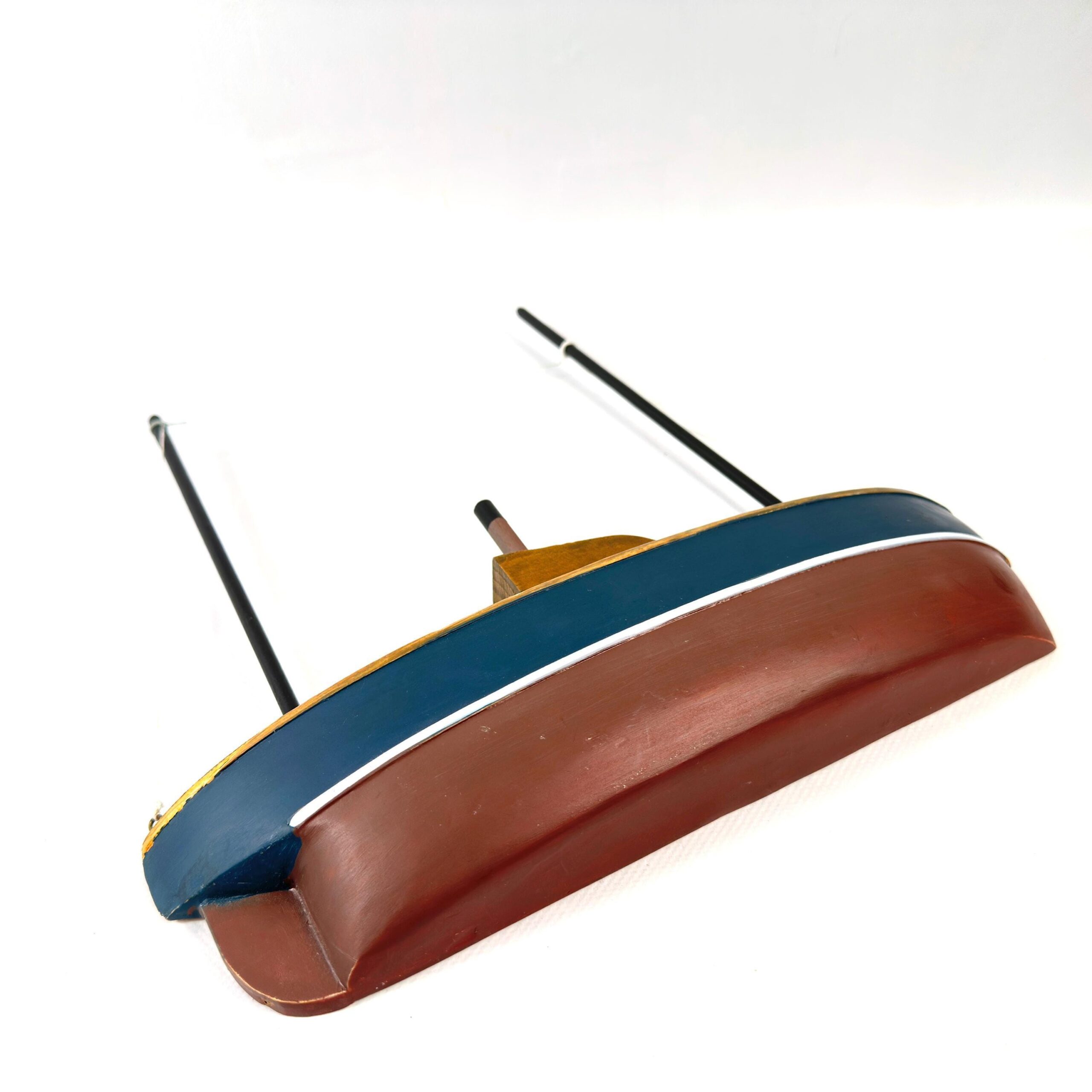 Wooden half-hull boat model angled view, navy stripe wrapping hull, burgundy lower section, cabin silhouette