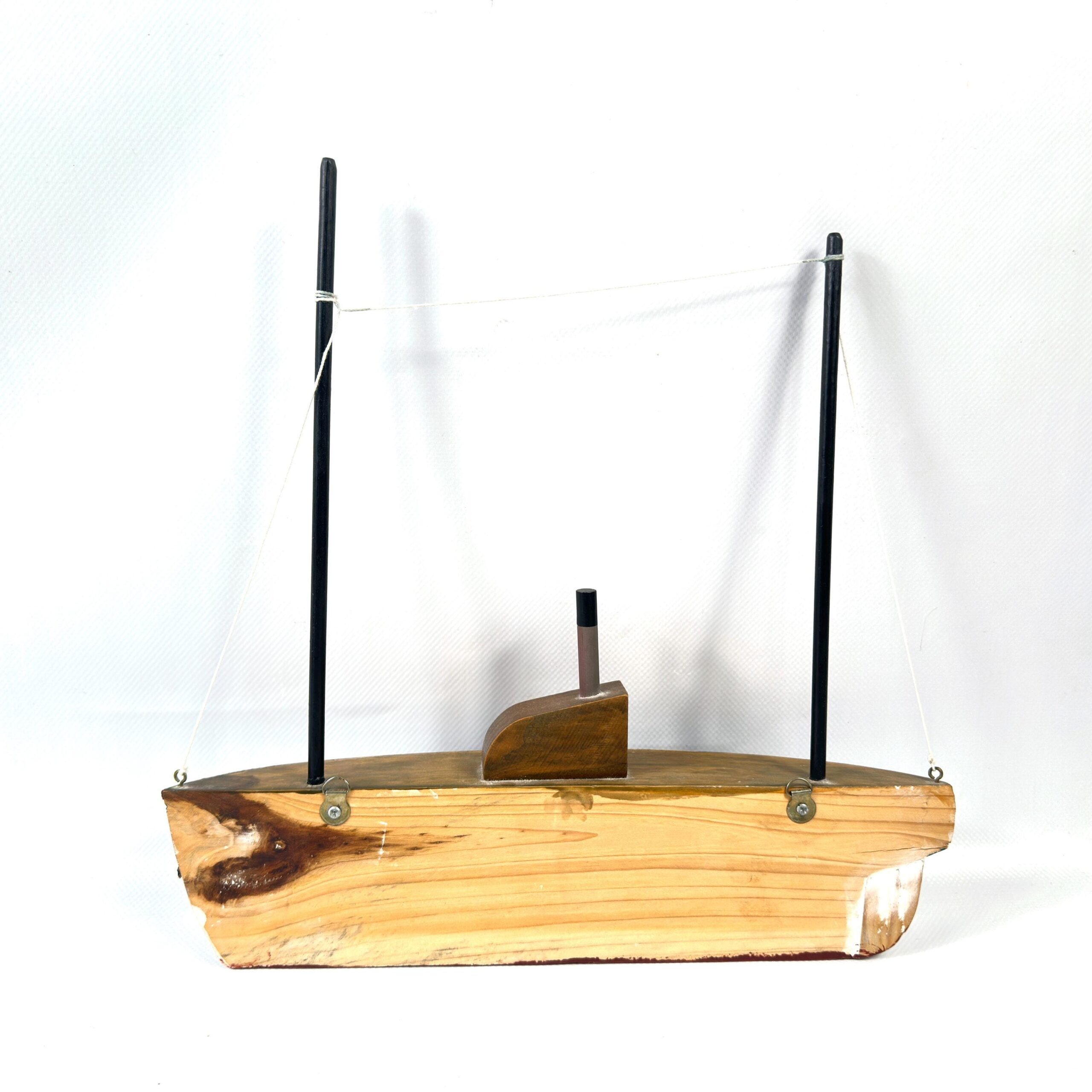 Wooden sailboat model from below, natural pine grain visible, navy and burgundy paint, weathered edge detail