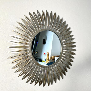 Silver sunburst mirror with radiating leaf-form frame, antiqued metallic finish, mid-century Hollywood Regency style wall dec