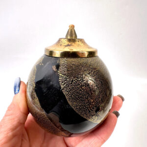 Vintage black glass oil lamp held in hand, spherical form with gold crackle texture and brass finial lid