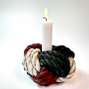 Hand-painted nautical rope knot candle holder in red, green, black, and cream, holding a lit taper candle, front view