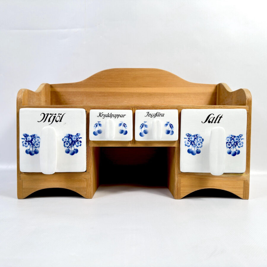 A complete Scandinavian kitchen solution—warm wood meets timeless blue-and-white ceramics in one thoughtful piece. Swedish wooden spice rack with blue-white ceramic jars labeled in Swedish, solid wood construction with curved details, 1997