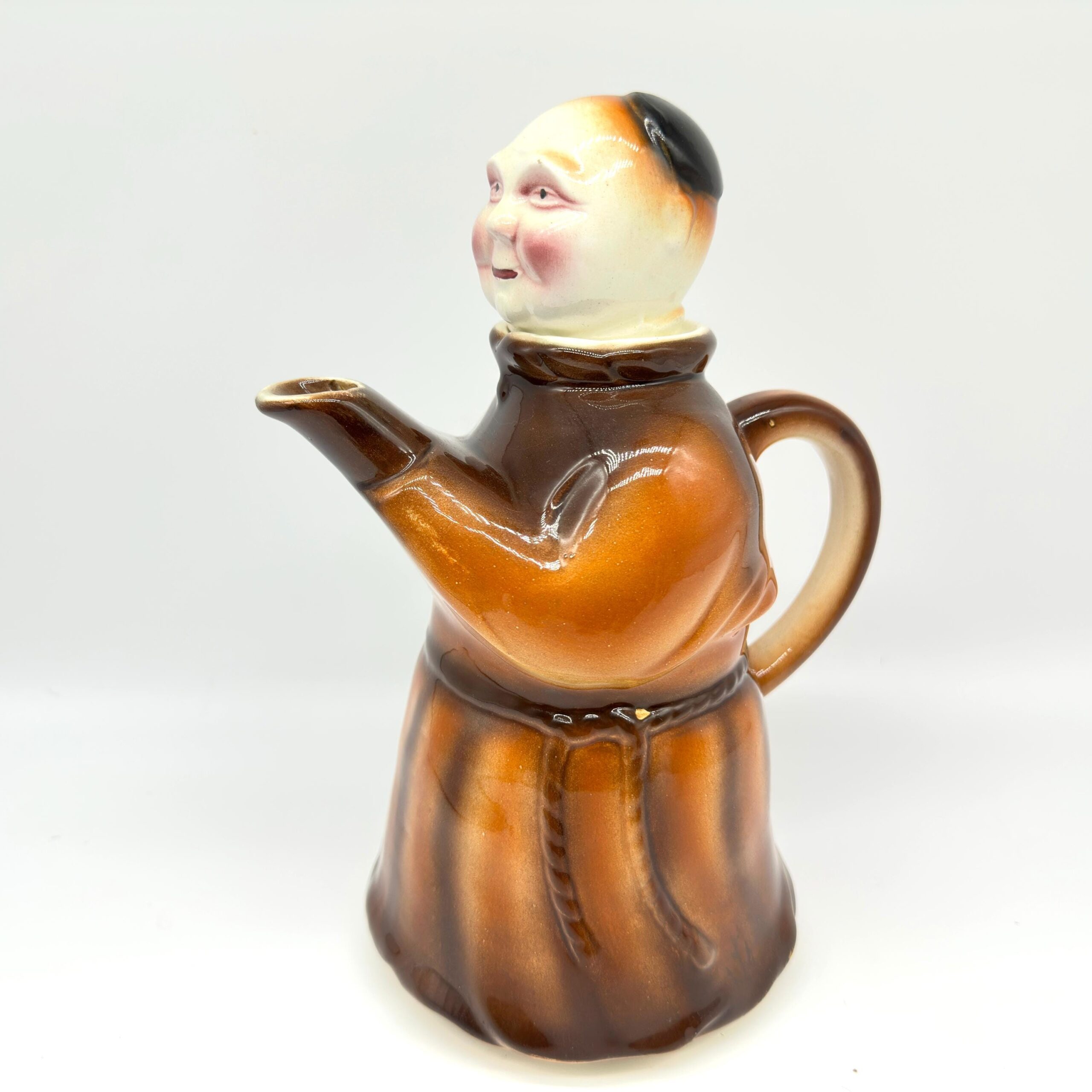 German 1950s monk teapot with removable ceramic head lid, brown robe and cream face against white background