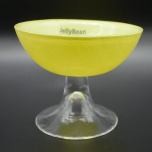 JellyBean yellow glass bowl with clear pedestal foot, angled view showing bright chartreuse bowl and transparent stem base