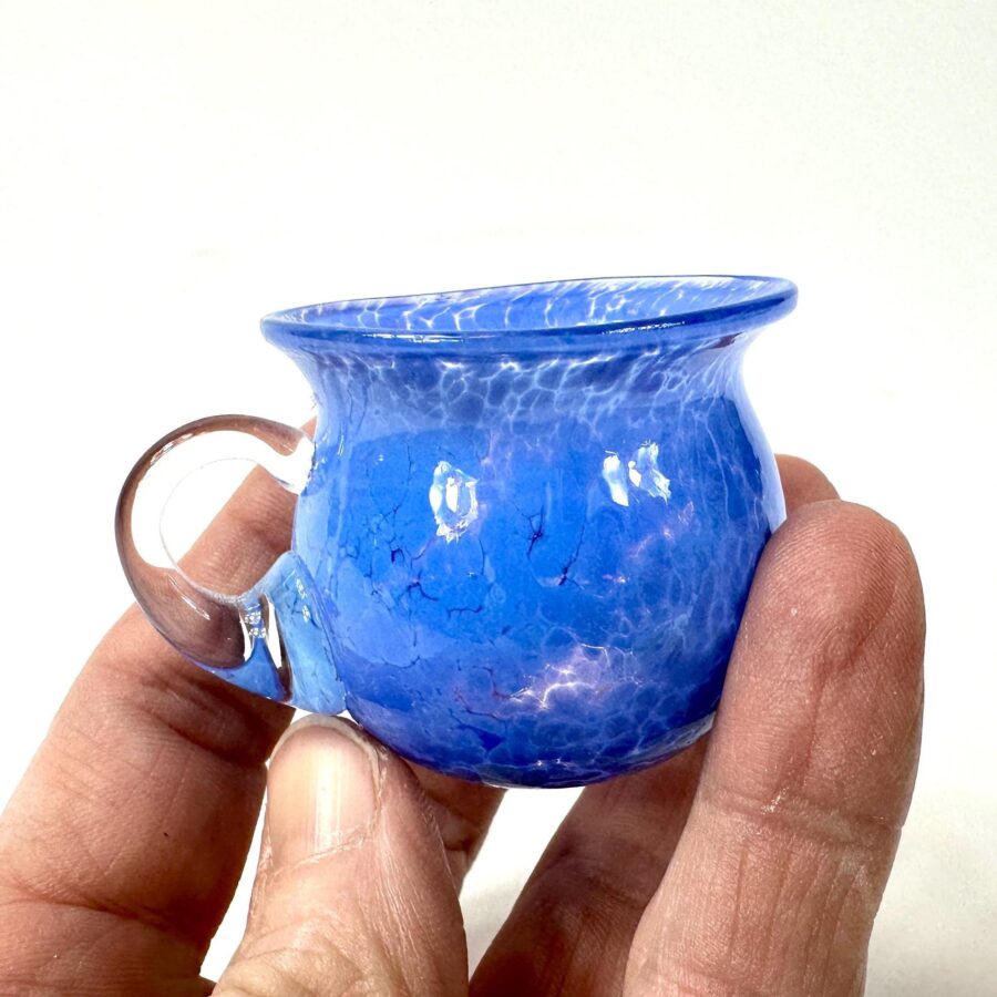 Cobalt blue vintage miniature glass cup held in palm, clear handle visible, crackle texture throughout