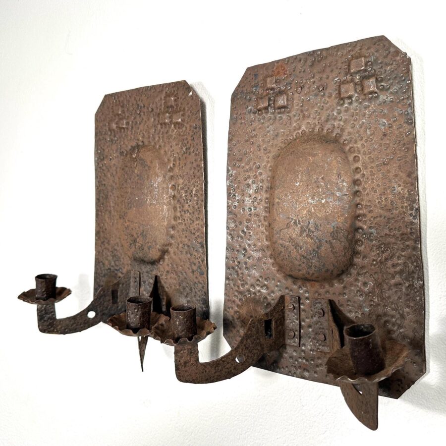 Pair of hand-forged wrought iron wall sconces with hammered backplates, cross motifs, and dual candle arms, gothic vintage st