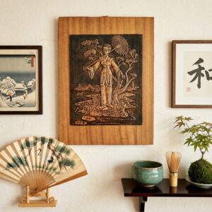 Vintage Japanese copper relief plaque mounted on wood, featuring kimono-clad geisha beneath parasol and flowering branches, s