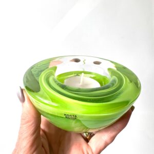 Kosta Boda Atoll bowl in lime green glass held in hands, showing nested rings and luminous color