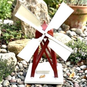 Red and white wooden Scandinavian garden windmill with rotating sails, displayed in garden setting with moss and stones