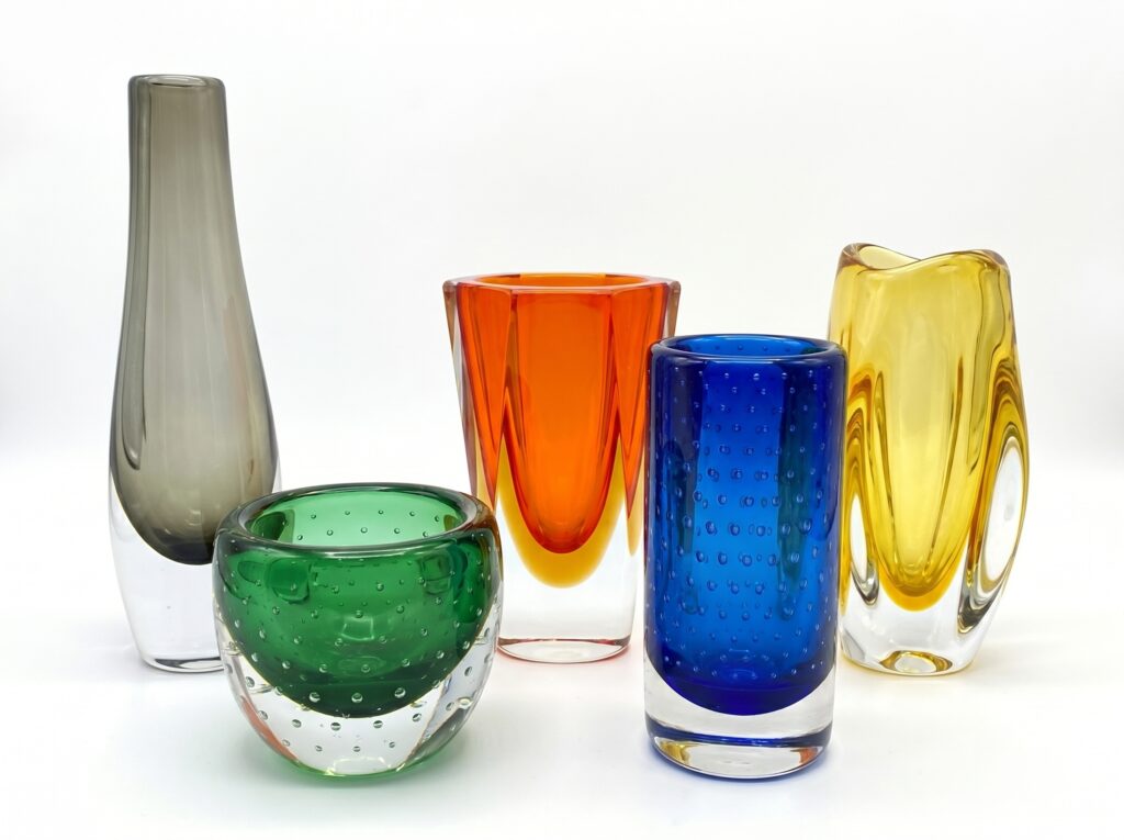 Array of vintage Swedish glass vessels including smoky grey tapered vase, green bowl, orange, blue and yellow cylindrical for