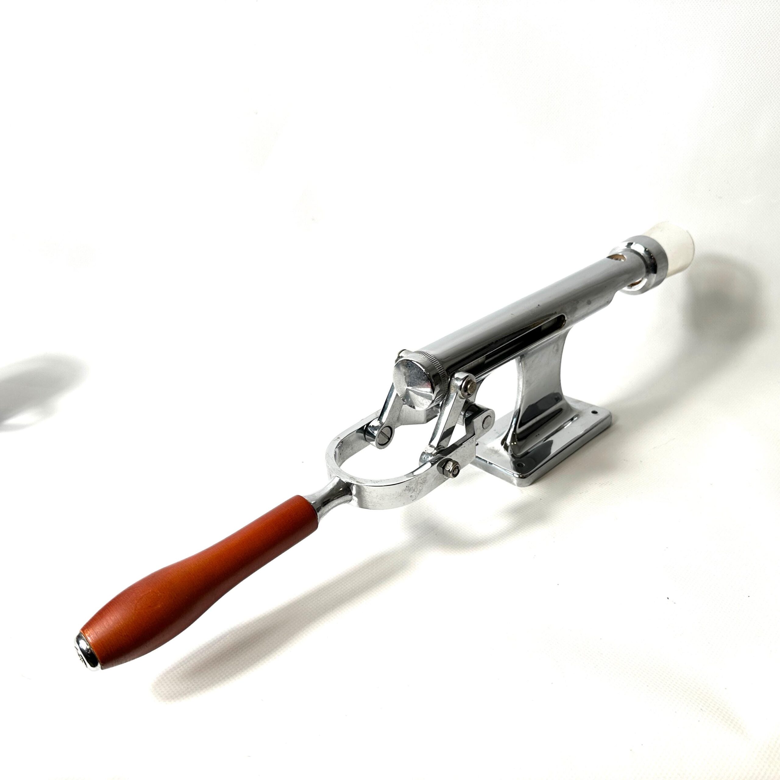 Flat lay angled view of vintage lever corkscrew against neutral background, red handle prominent, full mechanical skeleton vi