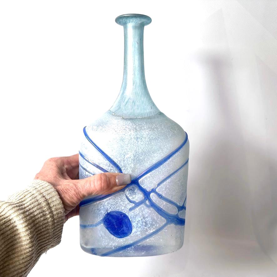 Bertil Vallien Galaxy bottle vase in frosted ice blue glass with cobalt blue abstract lines, held in hand showing full sculpt