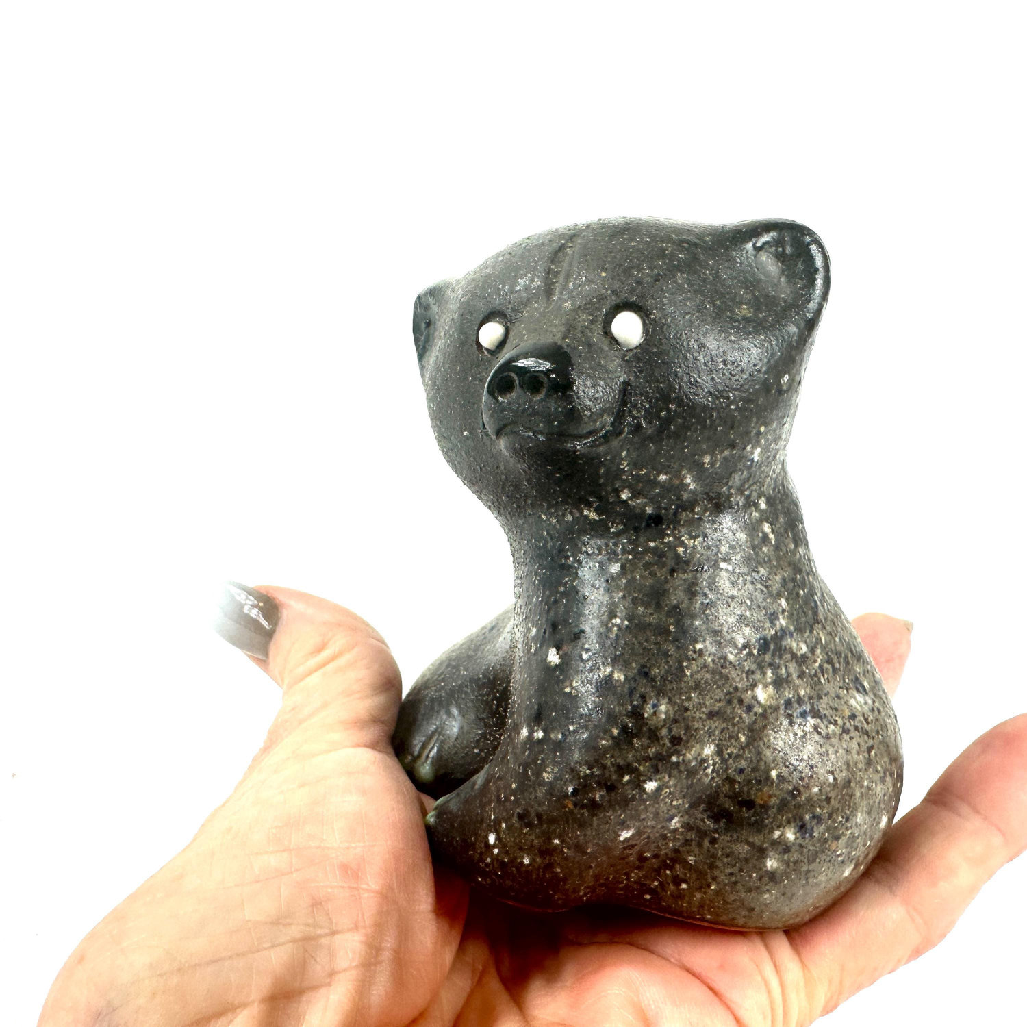 Ceramic bear in hand showing left side profile, articulated paws, speckled surface finish, and quiet Scandinavian charm