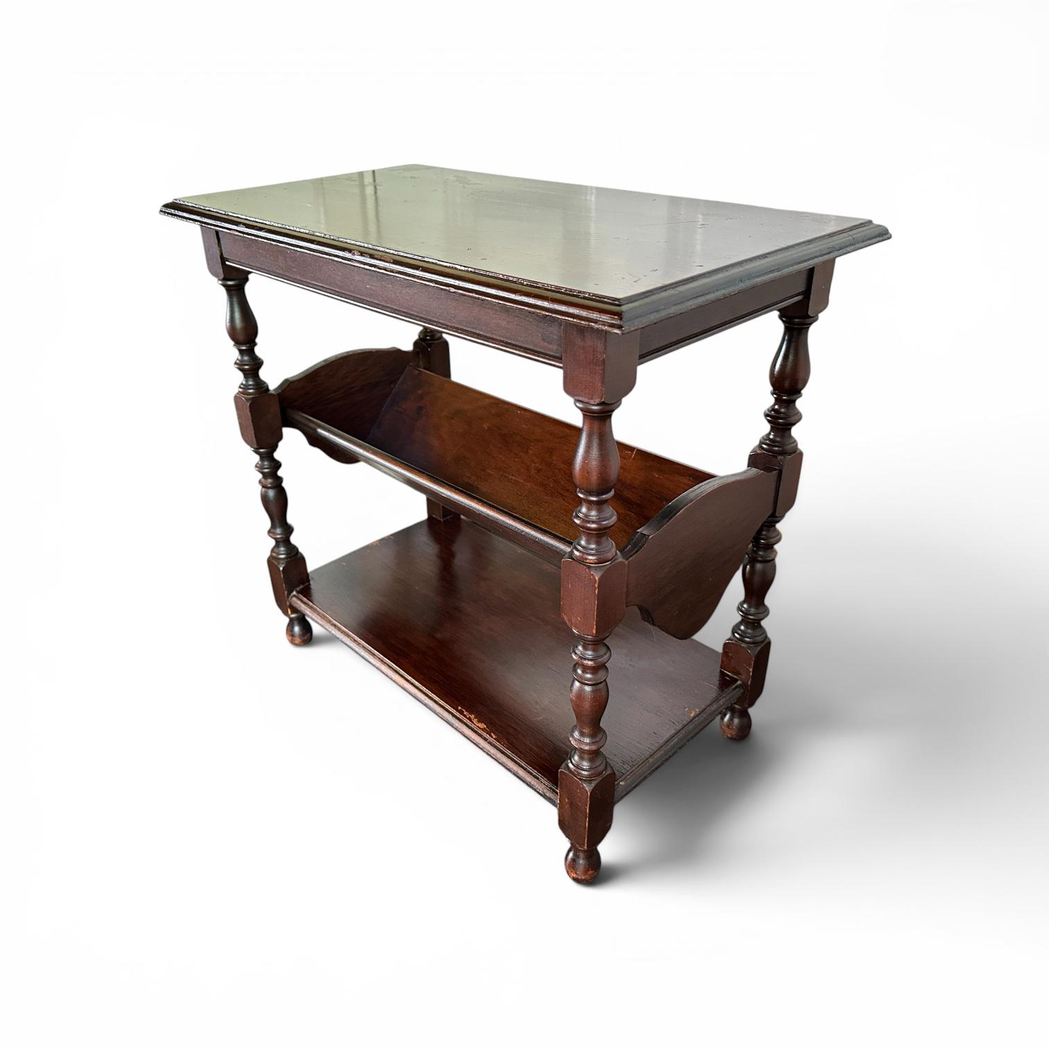 Dark wood table with glass-top surface and book storage shelf, angled view showing tabletop and supports