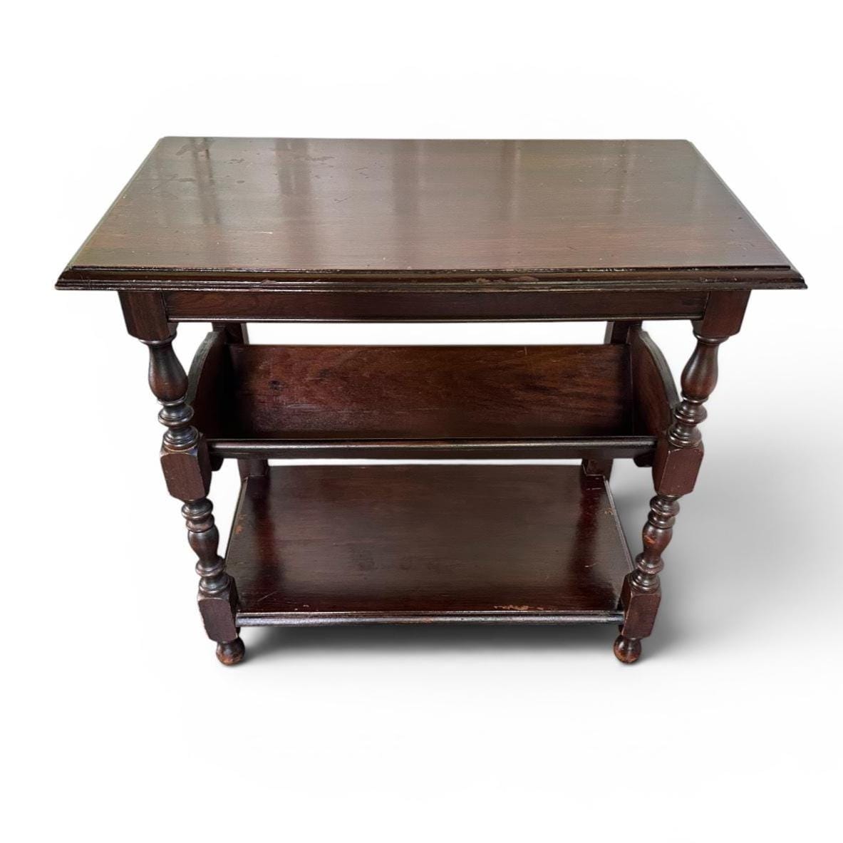 Dark wooden side table showing patinated surface, book shelf, lower tier, and turned support structure