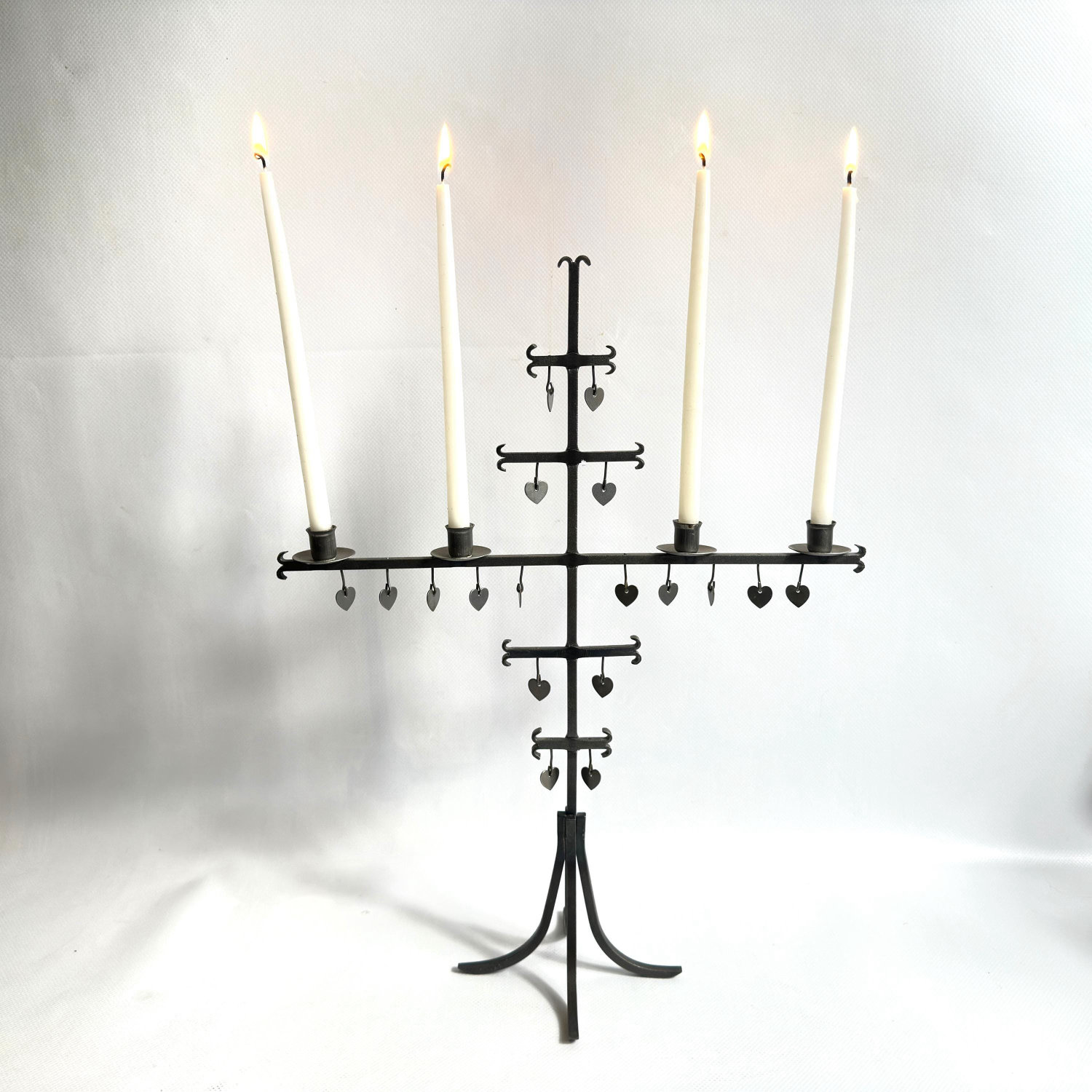 Full standing candelabra with four lit cream tapers, complete iron structure from tripod feet to candle arms, architectural S