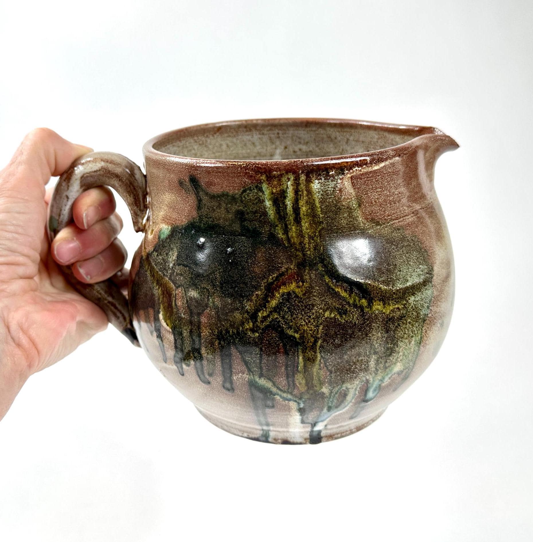 Hand-held Scandinavian studio pottery jug with abstract drip glaze in sage green and charcoal on warm stoneware