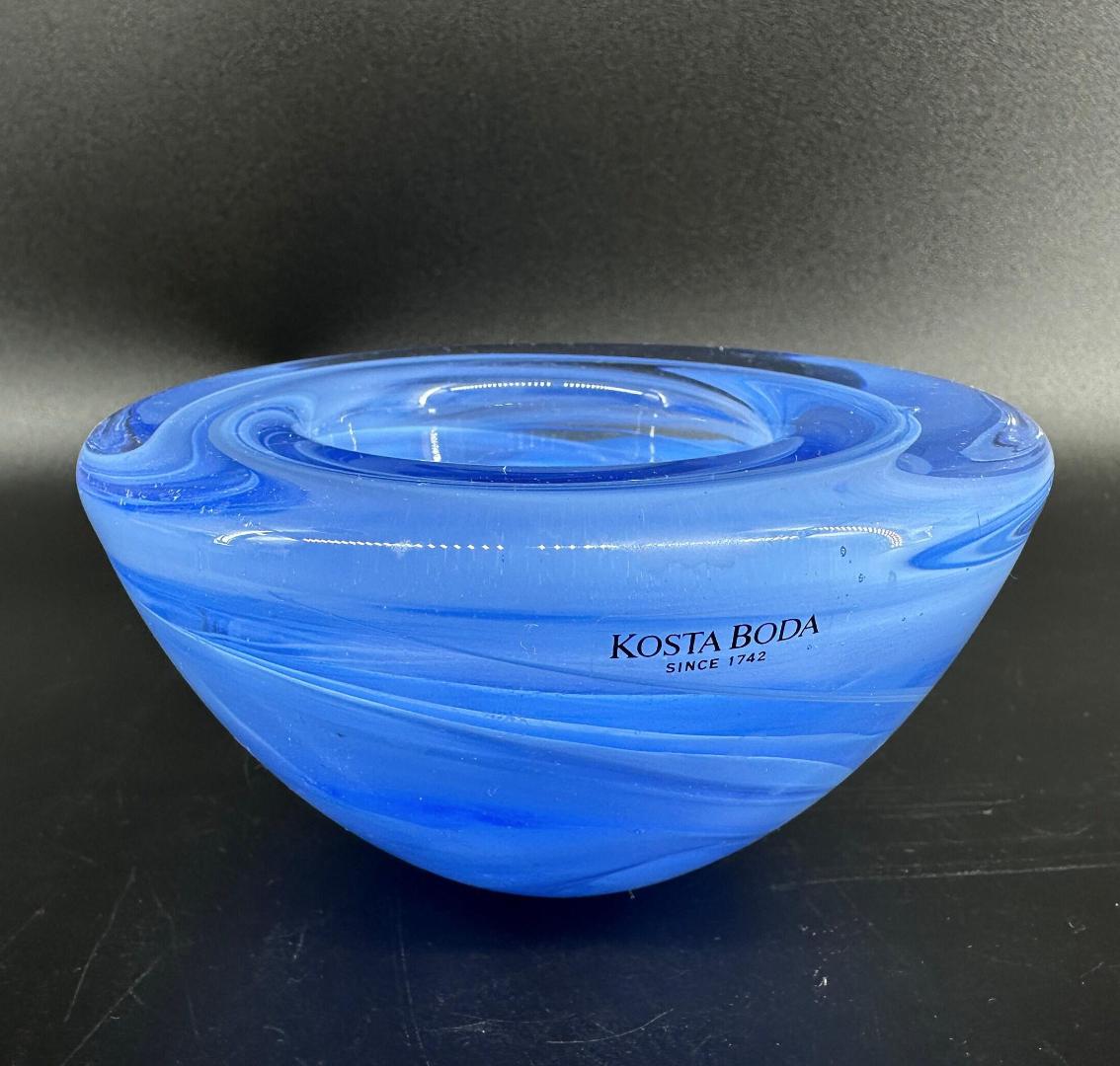 Kosta Boda Atoll blue glass bowl by Anna Ehrner, featuring swirled ink art pattern, shown from above against neutral backgrou