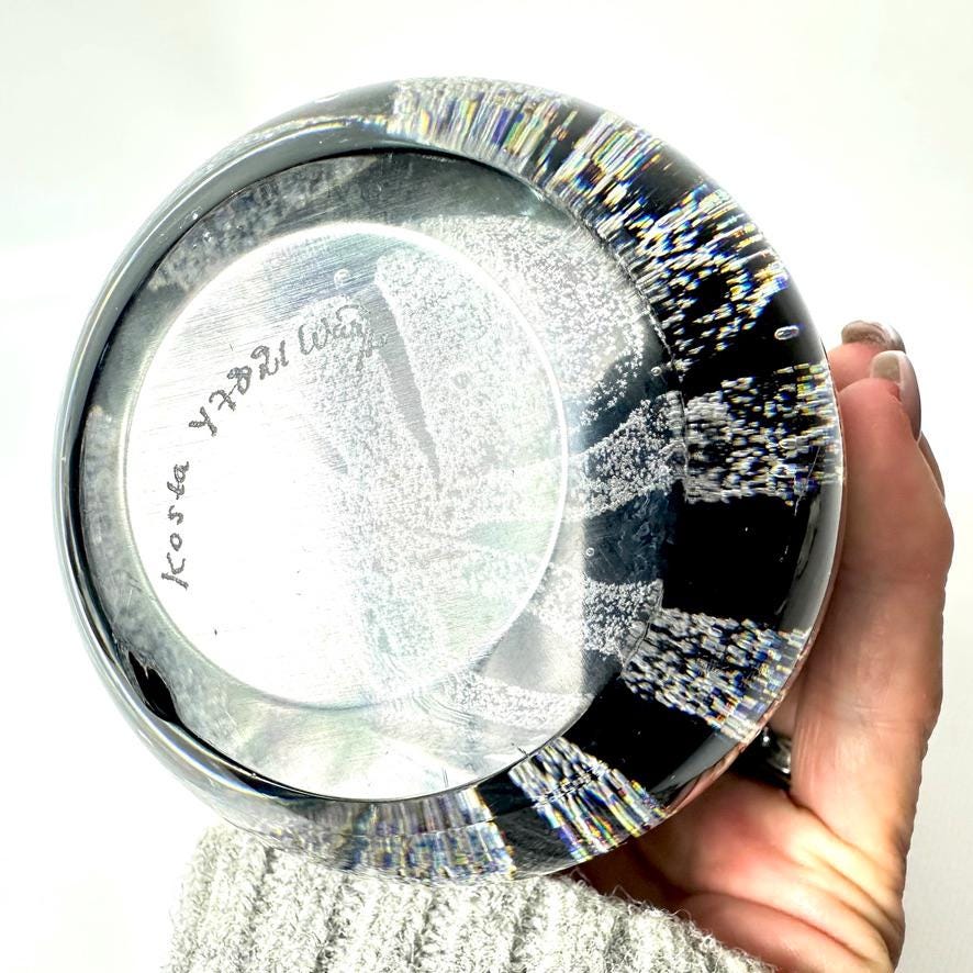 Kosta Boda vase bottom view held in hand, showing base construction, maker's details, and white bubble distribution