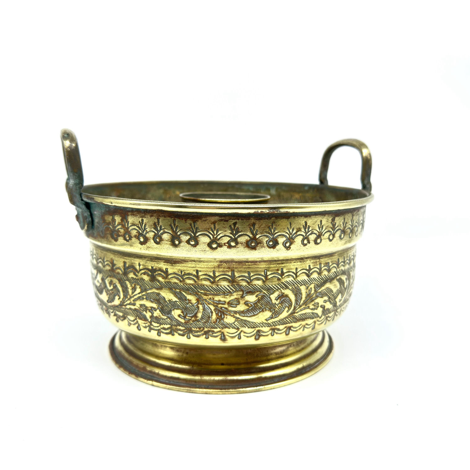Low-angle basin view emphasizing curved form, etched border patterns, and graceful dual handles in warm brass tones