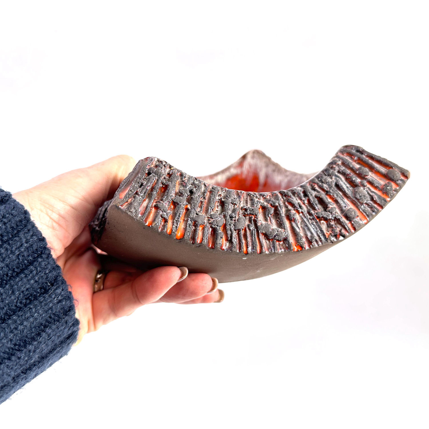 Norrmans Keramik lava bowl profile grip view displaying curved sculptural form, textured rim edge, and glowing orange-red gla