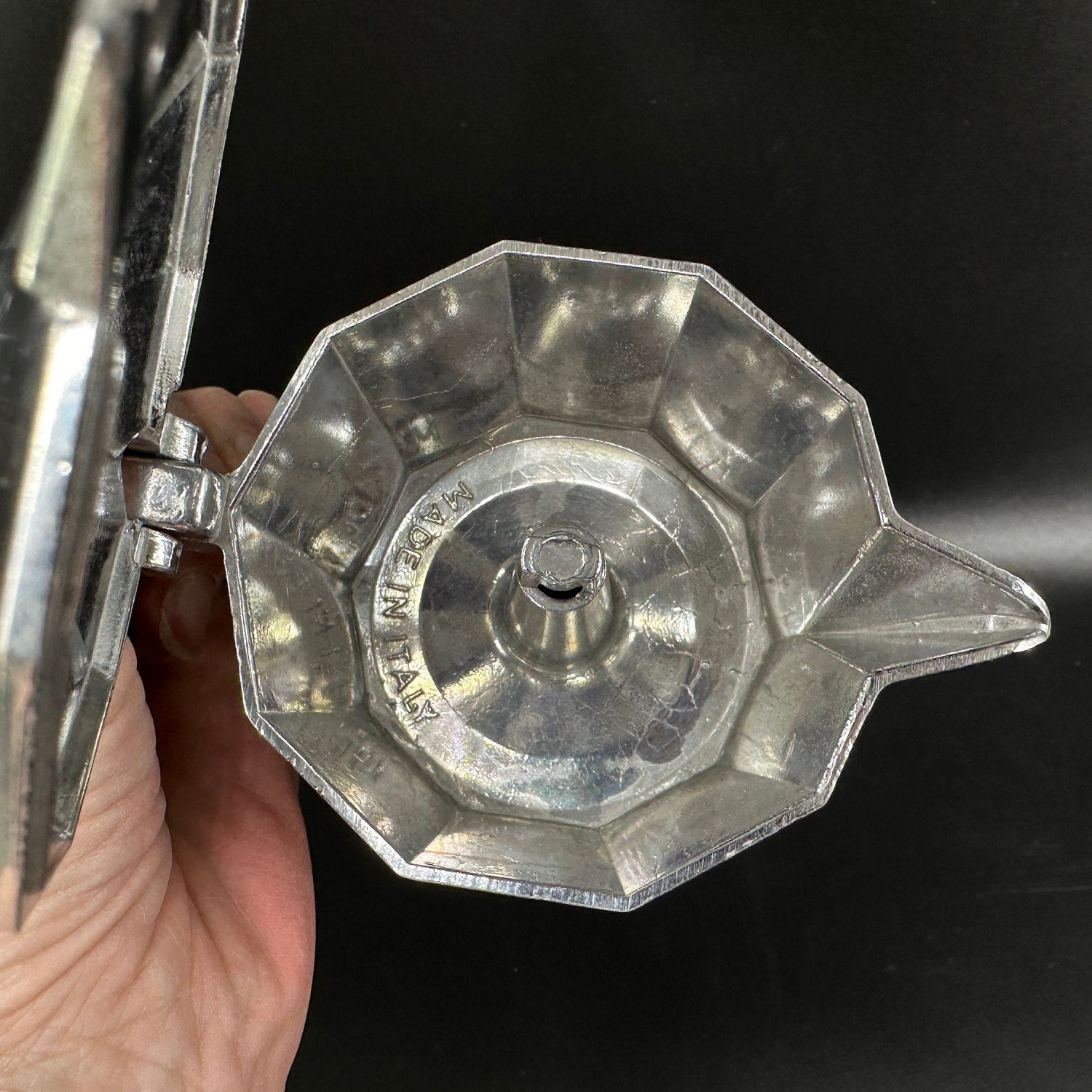 Overhead view of moka pot base showing octagonal pattern, internal filter mechanism, and brass valve