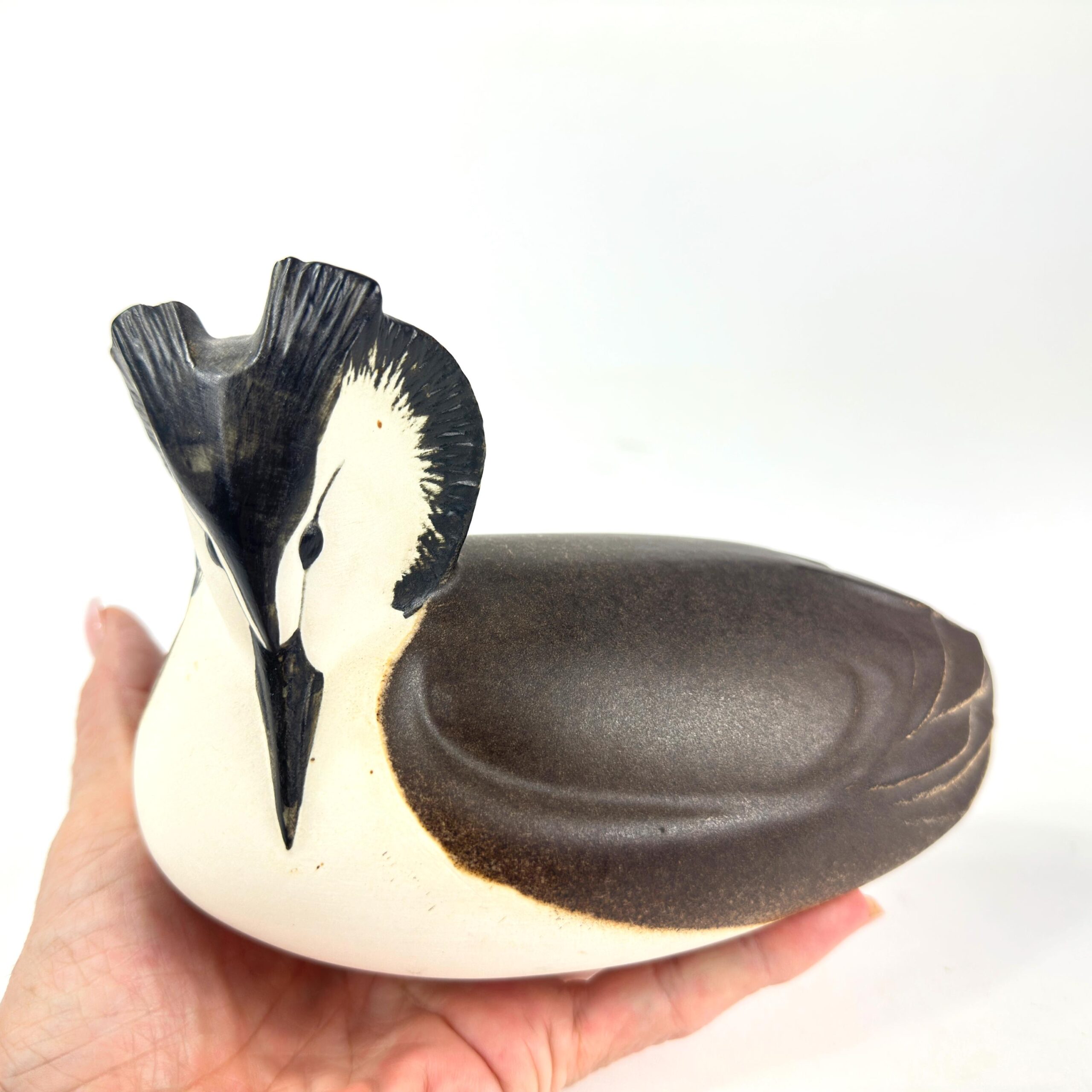 P. Hoff Swedish ceramic grebe sculpture, hand-painted cream and charcoal, held in palm showing scale and craftsmanship