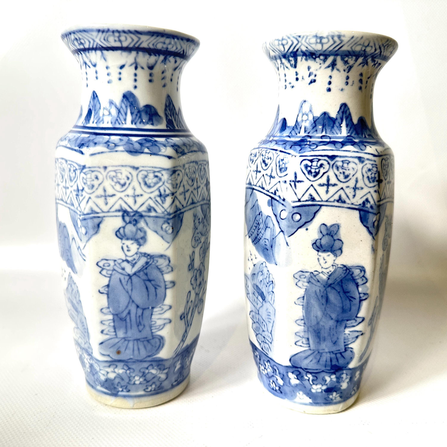 A matched pair of hand-painted vases with timeless chinoiserie design. Classic, elegant, ready to anchor any room. Pair of blue and white Chinese porcelain vases with traditional figural and floral panels, cream glaze