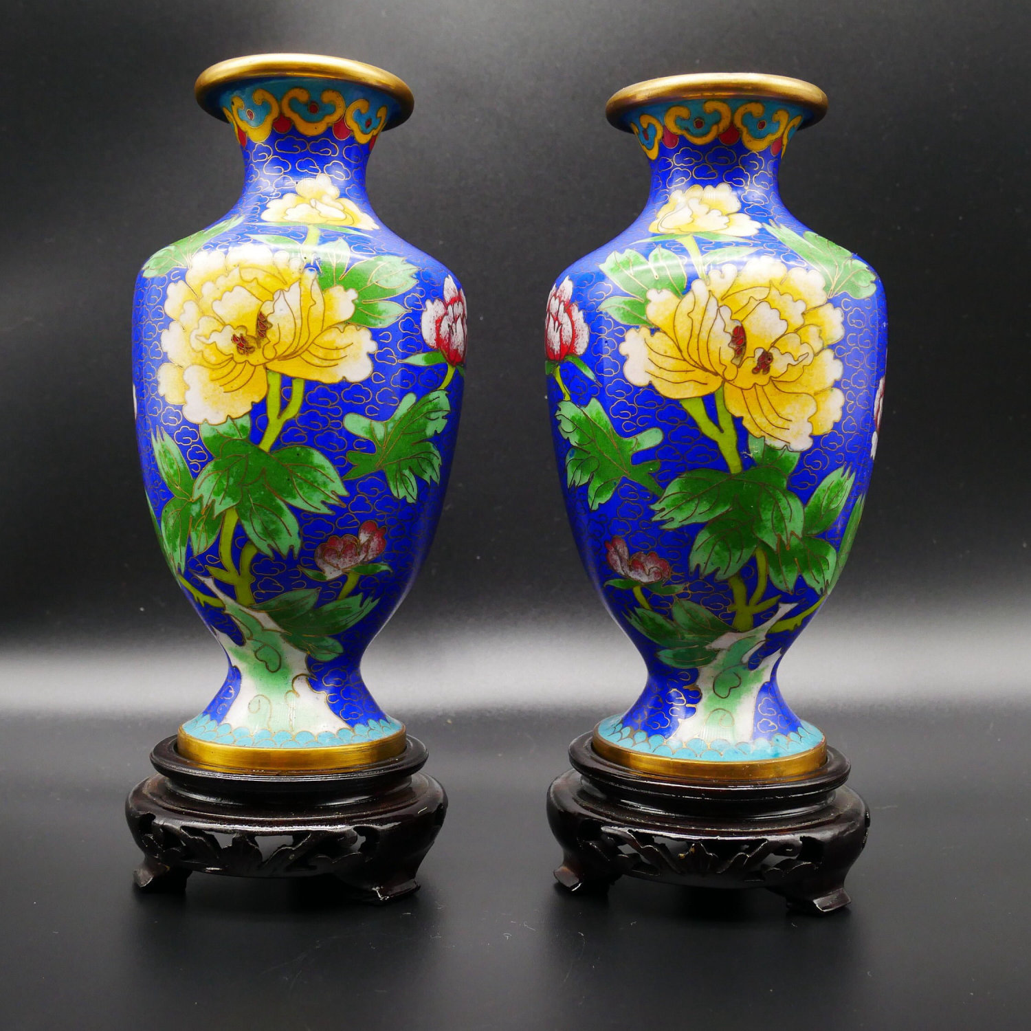 Pair of Chinese cloisonné vases with cobalt blue ground, yellow peonies, and green foliage, brass rims, on wooden stands