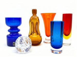 Vibrant collection of handblown Swedish glass vessels in cobalt blue, amber, orange, and red hues with crystal bowl.
