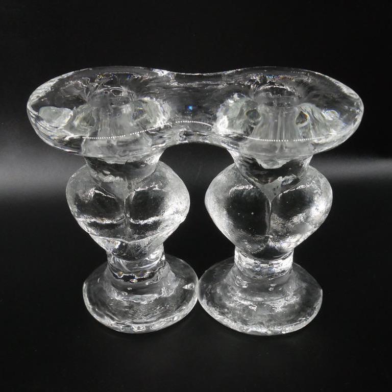 Side profile of glass heart candleholder pair, emphasizing bulbous body, narrow pedestal base, and molded contours