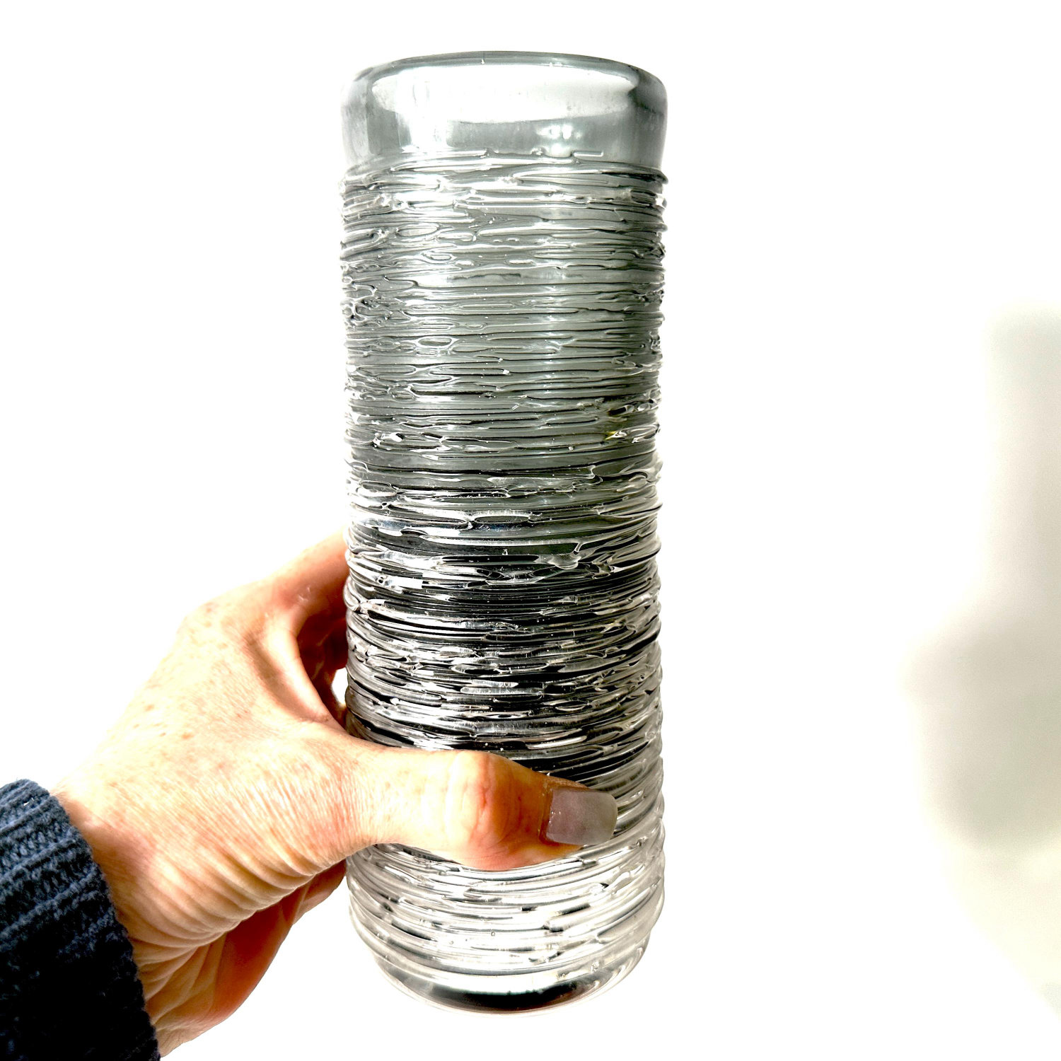 Skruf spun glass vase by Bengt Edenfalk held in hand, showing layered clear and smoky grey textured surface