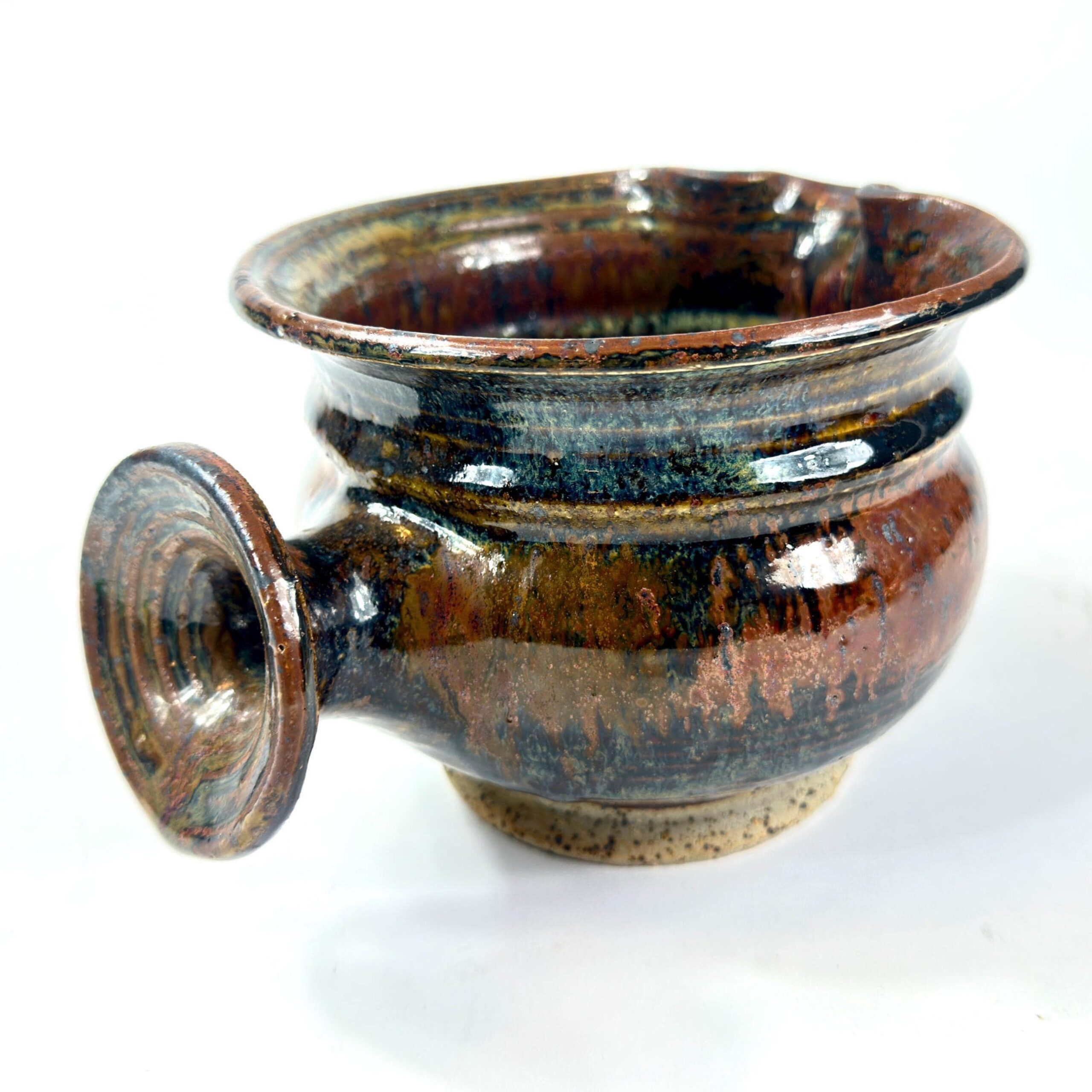 Studio pottery jug with layered drip glaze in brown, green, and blue stoneware, rounded body with handle and wide rim