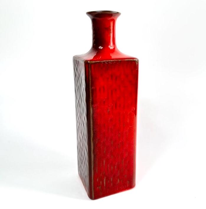 Scandinavian craftsmanship meets vibrant colour. A tactile red glaze defines this timeless mid-century vase. Swedish red ceramic vase with textured glaze, cylindrical form, narrow neck, mid-century design, front view
