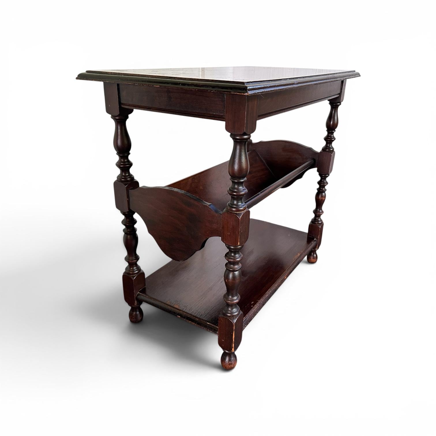 Three-tier dark wood storage table with turned supports and book rack, revealing depth and shelf capacity