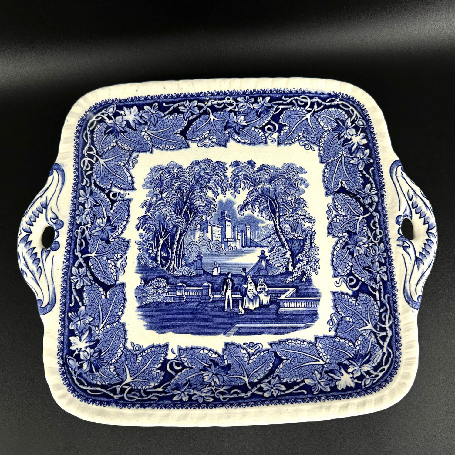 Square pink transferware platter flat lay showing complete Vista pattern with centered courtyard vignette and leafy surround