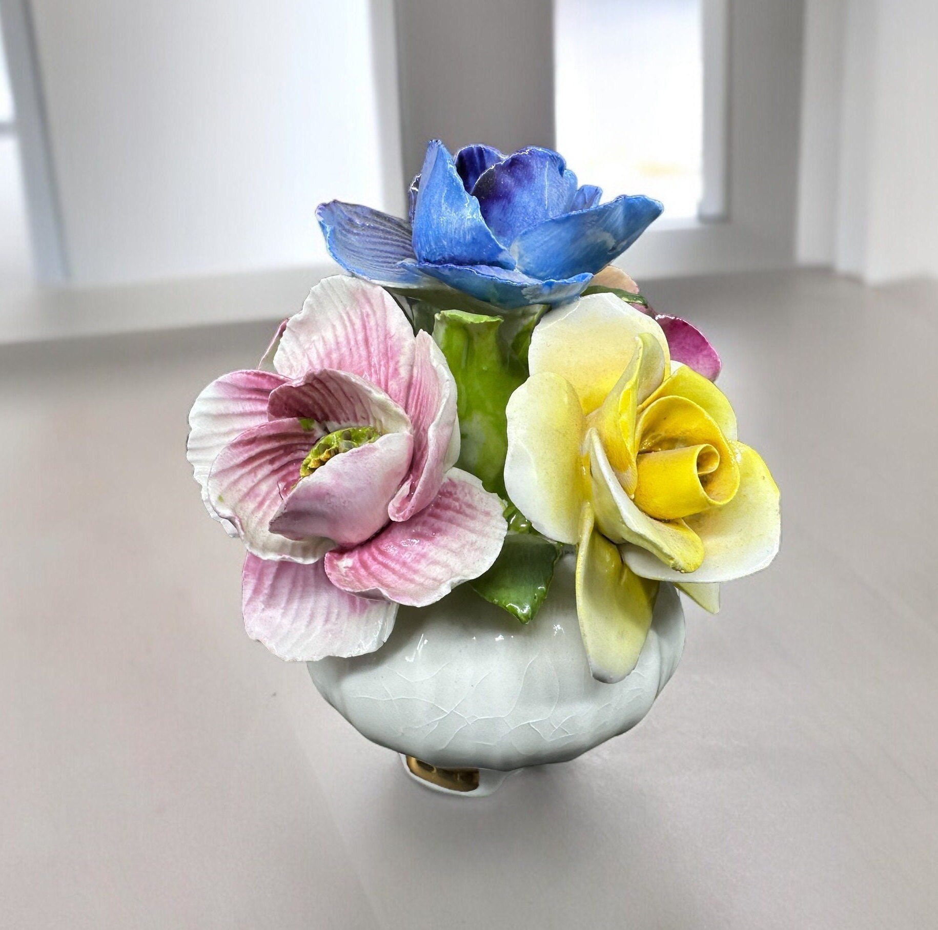 Vintage Jon Anton bone china flower basket featuring hand-painted blue, pink, and yellow blooms in white ceramic vessel