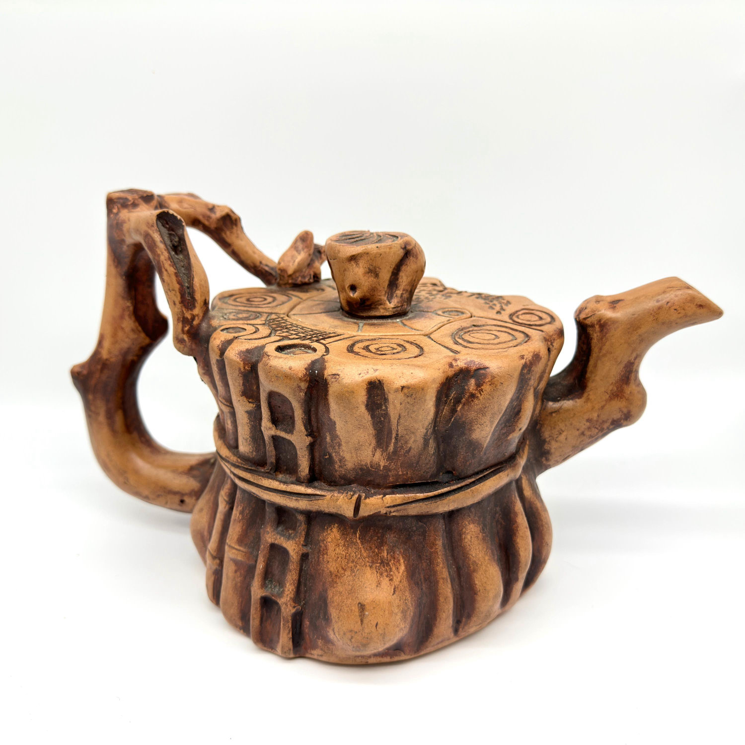 Yixing-style zisha clay teapot with sculpted tree trunk design and squirrel figurine perched on lid